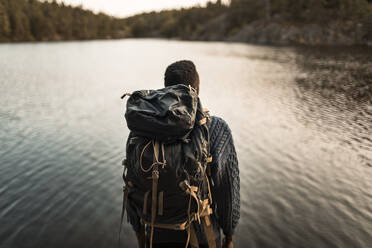 Rückansicht eines Mannes mit Rucksack gegen einen See im Wald - MASF20908