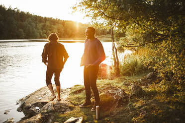 Male friends enjoying by lake in forest during vacation - MASF20928