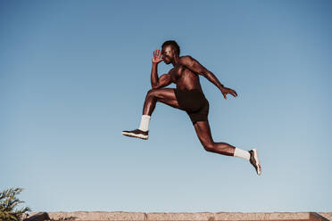 Young male athlete jumping over steps by clear sky during sunset - EBBF01397