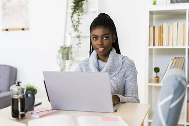Junge Frau, die zu Hause sitzend am Laptop lernt - GIOF09584
