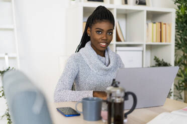 Woman studying through laptop while sitting at home - GIOF09585