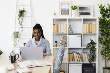 Female student E-learning on laptop while sitting at home - GIOF09588