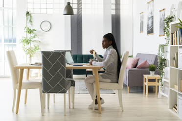 Young woman looking away while eating noddles at home - GIOF09641