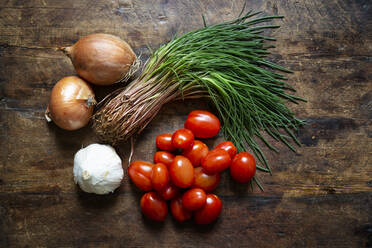 Fresh onions, garlic, tomatoes and agretti lying on wooden surface - MAMF01392