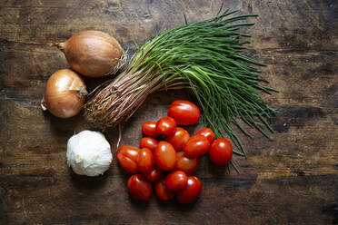 Frische Zwiebeln, Knoblauch, Tomaten und Agretti auf einer Holzunterlage - MAMF01392