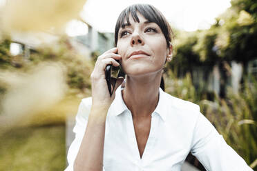 Selbstbewusste Geschäftsfrau schaut weg, während sie mit dem Handy telefoniert - JOSEF02238
