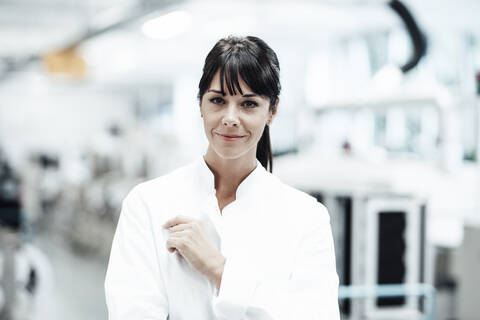 Confident smiling female scientist standing in bright laboratory stock photo