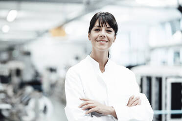 Smiling female scientist standing with arms crossed in bright laboratory - JOSEF02249