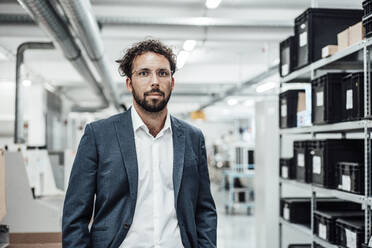 Confident businessman wearing eyeglasses while standing at industry - JOSEF02254