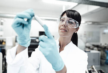 Smiling mature female scientist looking at sample in laboratory - JOSEF02301