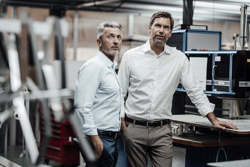 Männliche Ingenieure in Arbeitskleidung stehen an einer Werkbank in einer Fabrik - JOSEF02337