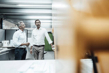 Männliche Ingenieure diskutieren im Stehen in einer Fabrik - JOSEF02367