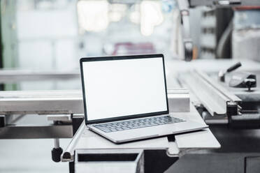 Laptop mit leerem Bildschirm an einer Maschine in einer Fabrik - JOSEF02397