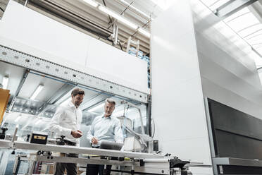 Male engineers discussing over laptop in factory - JOSEF02439