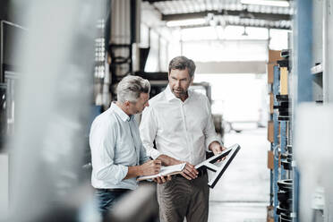 Male colleagues discussing over letter A while standing in manufacturing factory - JOSEF02446