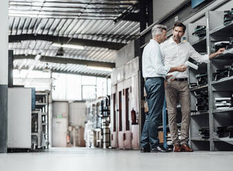 Male colleagues discussing over letter L in manufacturing factory - JOSEF02447