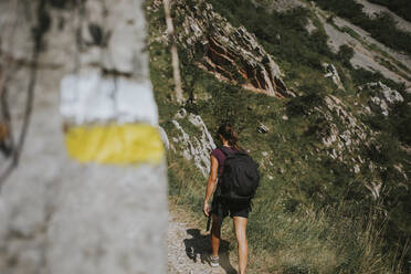 Female trekker with backpack walking at Las Xanas Route on sunny day - DMGF00265