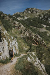 Woman walking on trail by rock formation during sunny day - DMGF00266