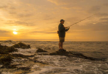 Ein Küstenfischer aus Maine wartet darauf, dass bei Sonnenaufgang ein gestreifter Wolfsbarsch anbeißt. - CAVF90219