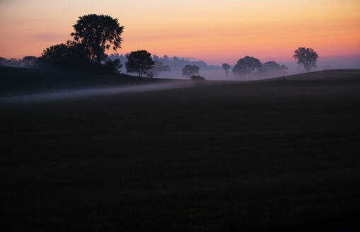 Das frühe Licht der Morgendämmerung erhellt den Bodennebel auf dem Ackerland - CAVF90220