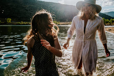 Close up of a happy mom and daughter playing in a lake - CAVF90280