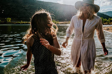 Nahaufnahme einer glücklichen Mutter und Tochter beim Spielen in einem See - CAVF90280