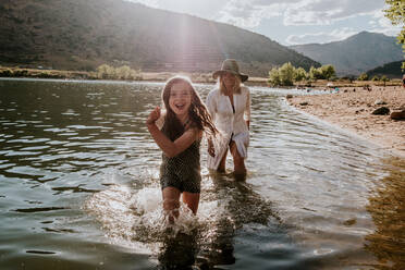 Smiling young girl running through water on a sunny afternoon - CAVF90282