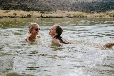 Glückliche Mutter und Tochter schwimmen an einem Sommertag in einem See - CAVF90289