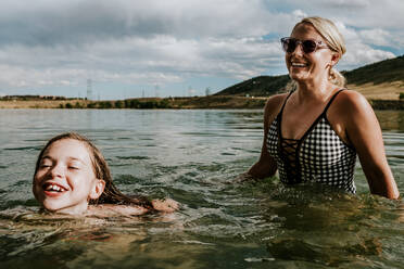 Mutter und Tochter spielen fröhlich an einem Sommertag in einem See - CAVF90290