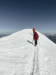 Two climbers ascending Mont Blanc on a glacier under blue sky - CAVF90315