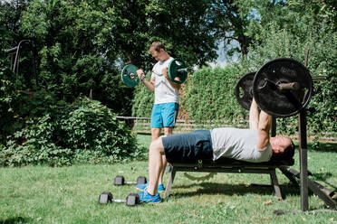 Zwei Männer trainieren zusammen in einem Fitnessstudio im Garten - CAVF90333