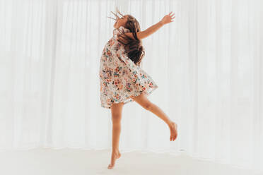 Wunderschönes multirassisches Mädchen tanzt in einem Kleid vor einem Vorhang - CAVF90341