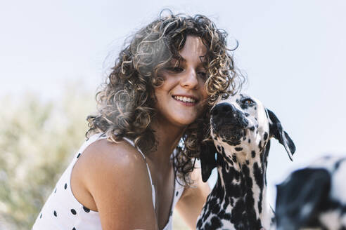 Lächelnde junge Frau mit Dalmatinerhund an einem sonnigen Tag - ABAYF00012