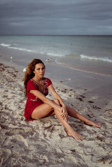 Beautiful woman sitting on shore at beach - MAUF03574