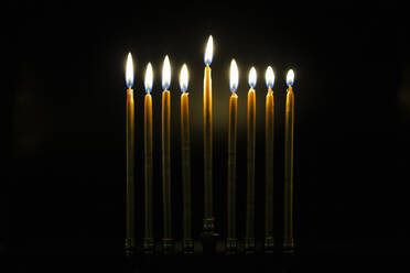 Beleuchtete goldene Chanukka-Kerzen im dunklen Zimmer - CAVF90342