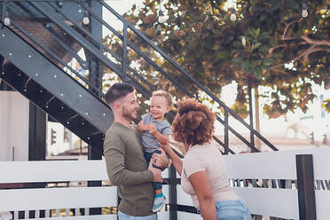 Papa hält einen kleinen Jungen und Mama versucht, ihn zum Lachen zu bringen - CAVF90350