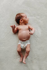 Neugeborenes Baby nur in einer Windel auf weißer Decke liegend - CAVF90374