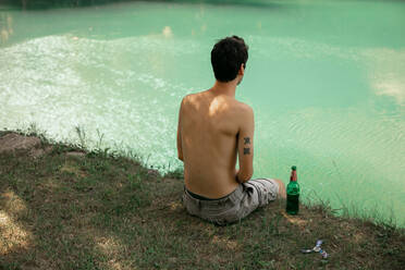 Back view of topless man sitting by the river - CAVF90403
