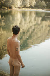 Rückenansicht eines am Fluss stehenden nackten Mannes - CAVF90406