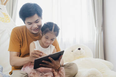 Little girl and young father are enjoying using tablet together. - CAVF90438