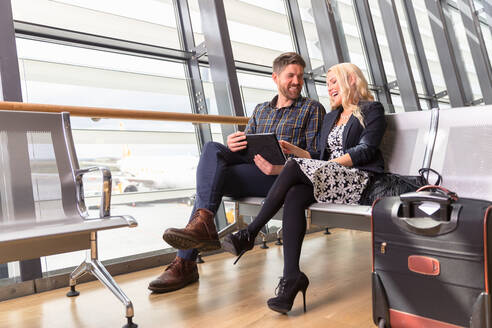 Glückliches Paar mit Tablet im Flughafen - CAVF90453