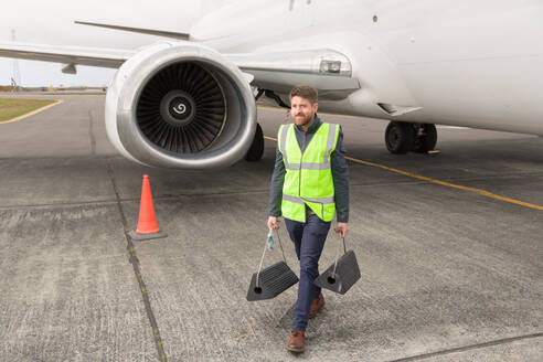 Männlicher Techniker geht mit Bremsen auf dem Flugplatz - CAVF90458