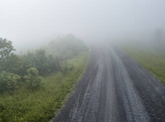 Leere, in dichten Nebel gehüllte Schotterstraße - BCDF00530