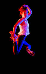 Junge Frau springt in der Luft vor schwarzem Hintergrund - STSF02651