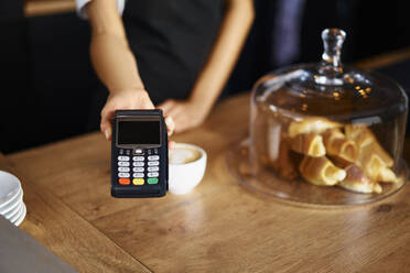 Midsection of waitress with credit card reader at cafe - BSZF01765