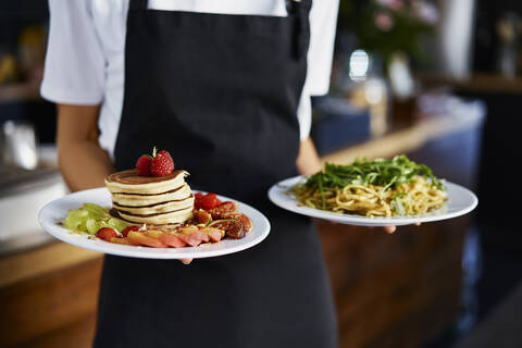 Midsection of female barista holding food plate in coffee shop stock photo