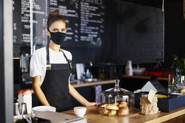 Porträt einer Kellnerin mit Gesichtsschutzmaske bei der Arbeit in einem Café - BSZF01776