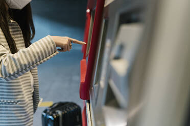 Female passenger buying ticket from kiosk during COVID-19 - EGAF00991