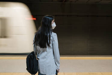 Weiblicher Fahrgast, der während der Pandemie auf seinen Zug im U-Bahnhof wartet - EGAF00998