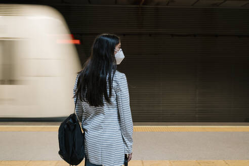 Female passenger waiting for her train at metro station during pandemic - EGAF00998